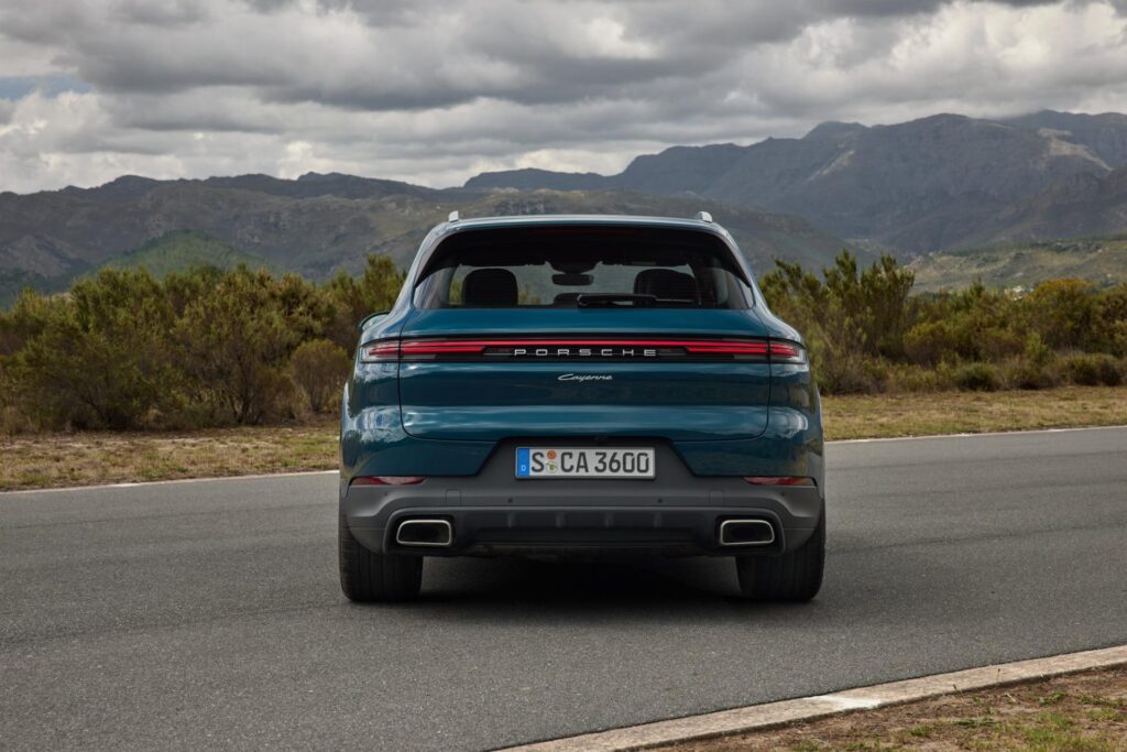 A blue Porsche Cayenne parks on a deserted road.