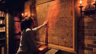 A woman points at a map in an escape room