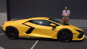 Doug DeMuro stands next to a new 2024 Lamborghini Revuelto supercar.