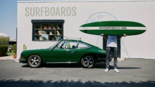 A man standing next to a vintage green Porsche with a surfboard reading, "Porsche"